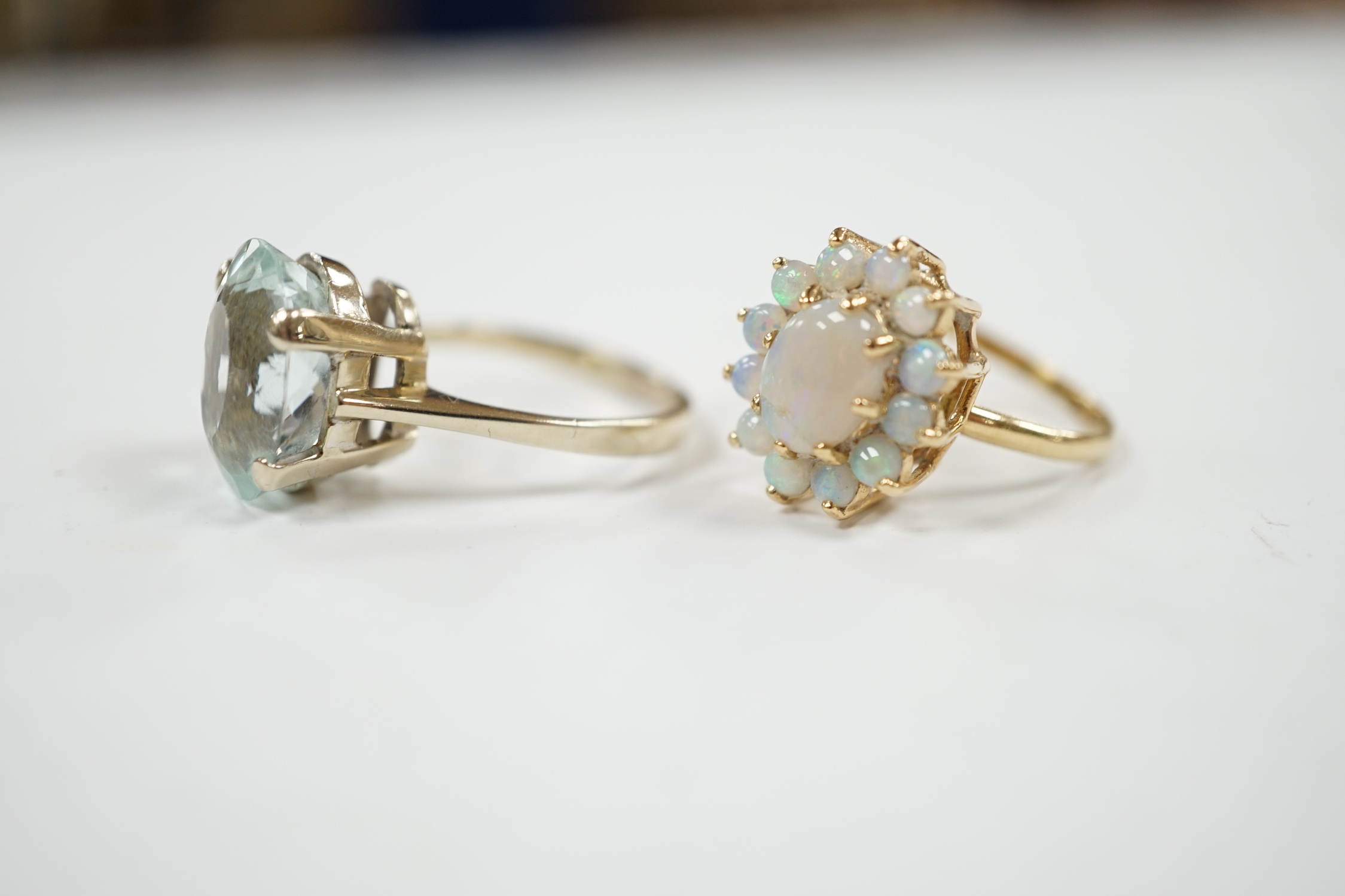 A 14k yellow metal and white opal set oval cluster ring, size P/Q, gross weight 4.1 grams and a gilt white metal? and oval fancy cut aquamarine set ring.